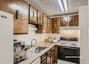 Thumbnail 4 of 20 - A kitchen with wooden cabinets and a white fridge.