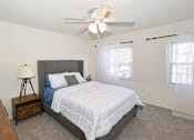 Thumbnail 5 of 23 - A bedroom with a bed, nightstand, and a ceiling fan.