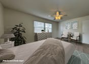 Thumbnail 12 of 23 - A bedroom with a large bed, a ceiling fan, and a potted plant.