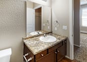 Thumbnail 12 of 25 - A bathroom with a granite countertop and a white sink.