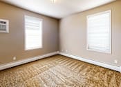 Thumbnail 21 of 25 - A room with a carpeted floor and two windows.