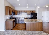Thumbnail 2 of 25 - A kitchen with wooden cabinets and a black refrigerator.