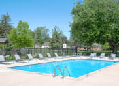 Thumbnail 21 of 27 - a swimming pool with chaise lounge chairs and trees in the background