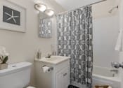 Thumbnail 11 of 25 - a bathroom with white fixtures and a black and white shower curtain