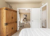Thumbnail 6 of 24 - a bedroom with a bed and a dresser and a living room