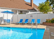 Thumbnail 10 of 24 - a swimming pool with blue chairs and umbrellas in front of a hotel pool