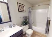 Thumbnail 12 of 27 - A bathroom with a toilet, sink, and shower.
