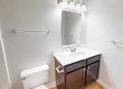 Thumbnail 13 of 27 - A white toilet sits next to a sink in a small bathroom.
