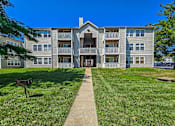 Thumbnail 26 of 27 - A large apartment complex with a grassy area in front.