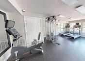 Thumbnail 21 of 27 - A gym with treadmills, elliptical machines, and other exercise equipment.