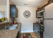 Thumbnail 2 of 30 - a kitchen with stainless steel appliances and granite counter tops