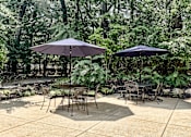 Thumbnail 31 of 37 - A patio with a table and chairs under umbrellas.