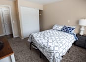 Thumbnail 7 of 26 - A bedroom with a bed, nightstand, and two doors.