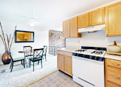 Thumbnail 2 of 16 - A kitchen with a white stove and wooden cabinets.