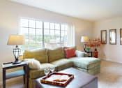 Thumbnail 5 of 16 - A living room with a green couch and a brown coffee table.