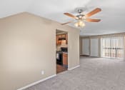 Thumbnail 9 of 27 - an empty living room with a ceiling fan and a kitchen