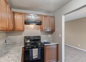 Thumbnail 3 of 27 - an empty kitchen with wood cabinets and a black stove