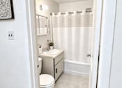 Thumbnail 8 of 18 - A white bathroom with a toilet, sink, and shower.