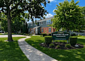 Thumbnail 19 of 19 - A sign for Golfview Village Townhomes is in the foreground of a well kept lawn.