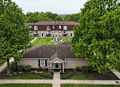 Thumbnail 1 of 14 - A building with a brown roof is surrounded by trees.