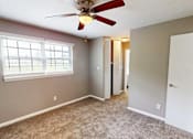 Thumbnail 8 of 18 - A room with a ceiling fan and carpeted floor.