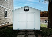 Thumbnail 9 of 18 - A white shed with a black logo on the top.