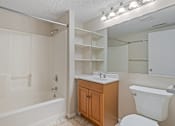 Thumbnail 8 of 26 - A white bathroom with a wooden cabinet and a white toilet.