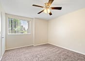Thumbnail 5 of 26 - A room with a ceiling fan and carpeted floor.
