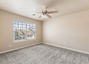 Thumbnail 10 of 29 - A room with a ceiling fan and a window showing a view of a house.