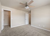 Thumbnail 9 of 29 - A room with a ceiling fan and carpeted floor.