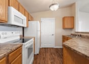 Thumbnail 2 of 29 - A kitchen with white appliances and wooden cabinets.