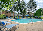 Thumbnail 19 of 24 - A pool surrounded by trees and chairs.