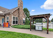 Thumbnail 22 of 29 - A brick house with a grill and a play structure outside.