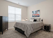 Thumbnail 10 of 38 - A bedroom with a bed, nightstand, and a painting on the wall.