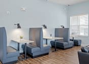 Thumbnail 23 of 38 - A room with blue walls and gray chairs and tables. The apartments businesscenter.