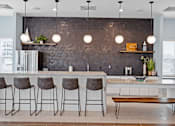 Thumbnail 22 of 38 - A kitchen with a bar area and four bar stools.