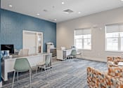 Thumbnail 24 of 38 - A modern office space with a blue accent wall and a variety of chairs and desks.