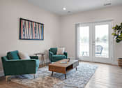 Thumbnail 13 of 38 - A living room, with glass doors that open to a patio. A coffee table with two accent chair around it.