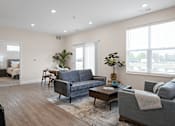 Thumbnail 8 of 38 - A living room with a grey couch and a coffee table.