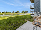 Thumbnail 32 of 38 - A patio with chairs and a view of a grassy field and trees.