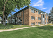 Thumbnail 22 of 22 - a brick apartment building with green grass and trees