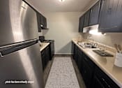 Thumbnail 4 of 16 - Apartment kitchen with cabinets and a stainless steel refrigerator