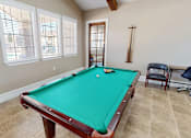 Thumbnail 15 of 30 - A pool table in a room with a chair and a window.