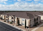 Thumbnail 26 of 30 - Apartment complex with a parking lot in front.