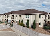 Thumbnail 25 of 30 - A large, two-story residential building with a brown roof and a grey exterior.