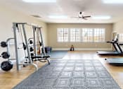 Thumbnail 19 of 30 - A spacious home gym with a weight bench, treadmill, and a ceiling fan.