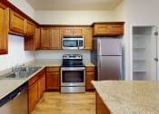 Thumbnail 1 of 16 - a kitchen with wooden cabinets and stainless steel appliances