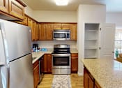 Thumbnail 1 of 30 - A kitchen with wooden cabinets and a stainless steel refrigerator.