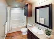 Thumbnail 8 of 25 - A bathroom with a white toilet, sink, and a mirror.