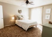 Thumbnail 3 of 25 - A bedroom with a bed, a ceiling fan, and a carpeted floor.